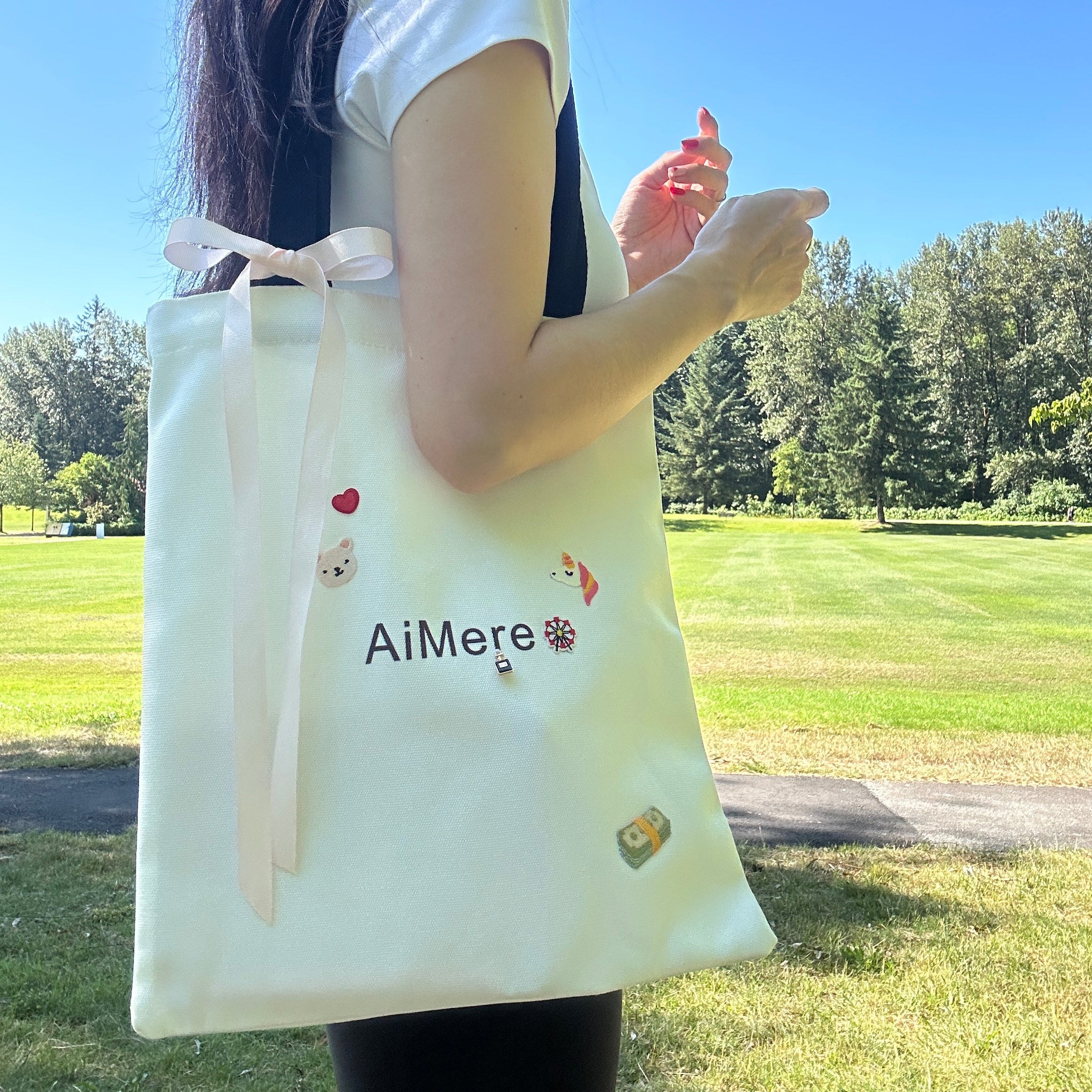 Person holding a white bag with 'AiMere' branding outdoors on a sunny day.