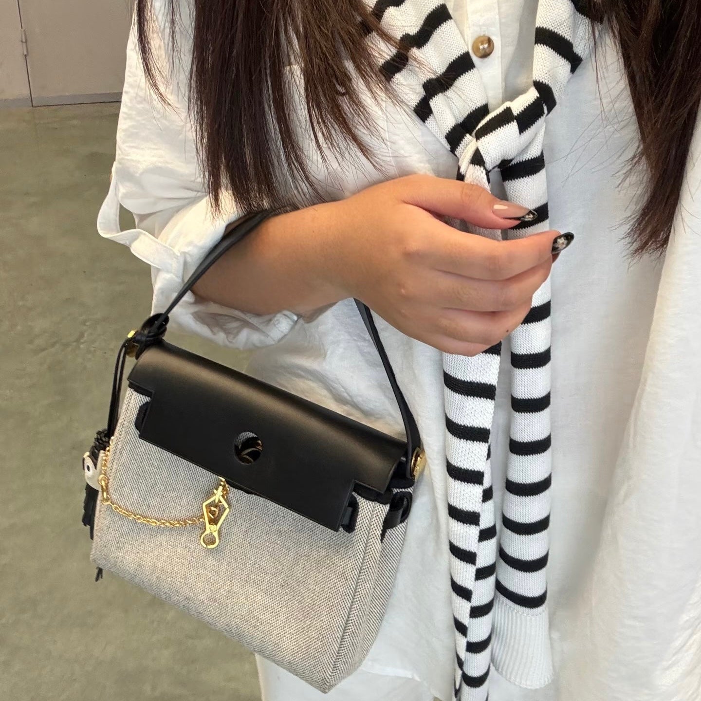 Person holding a herbag with a striped scarf draped over shoulders