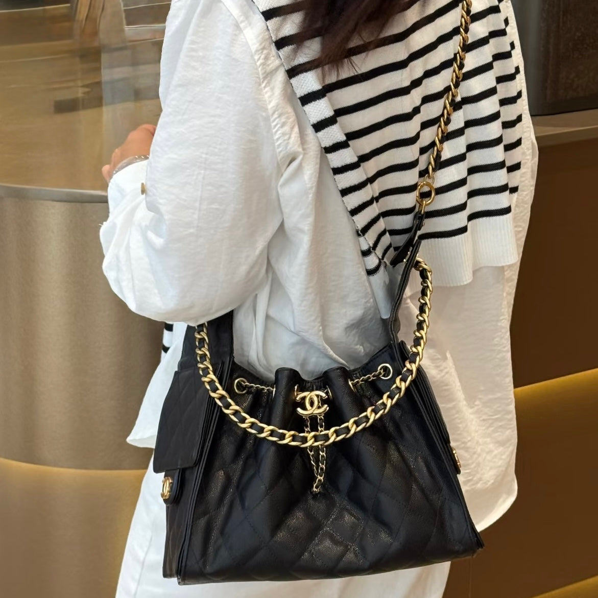 Person wearing a black Chanel 25 bag converted into a crossbody bag