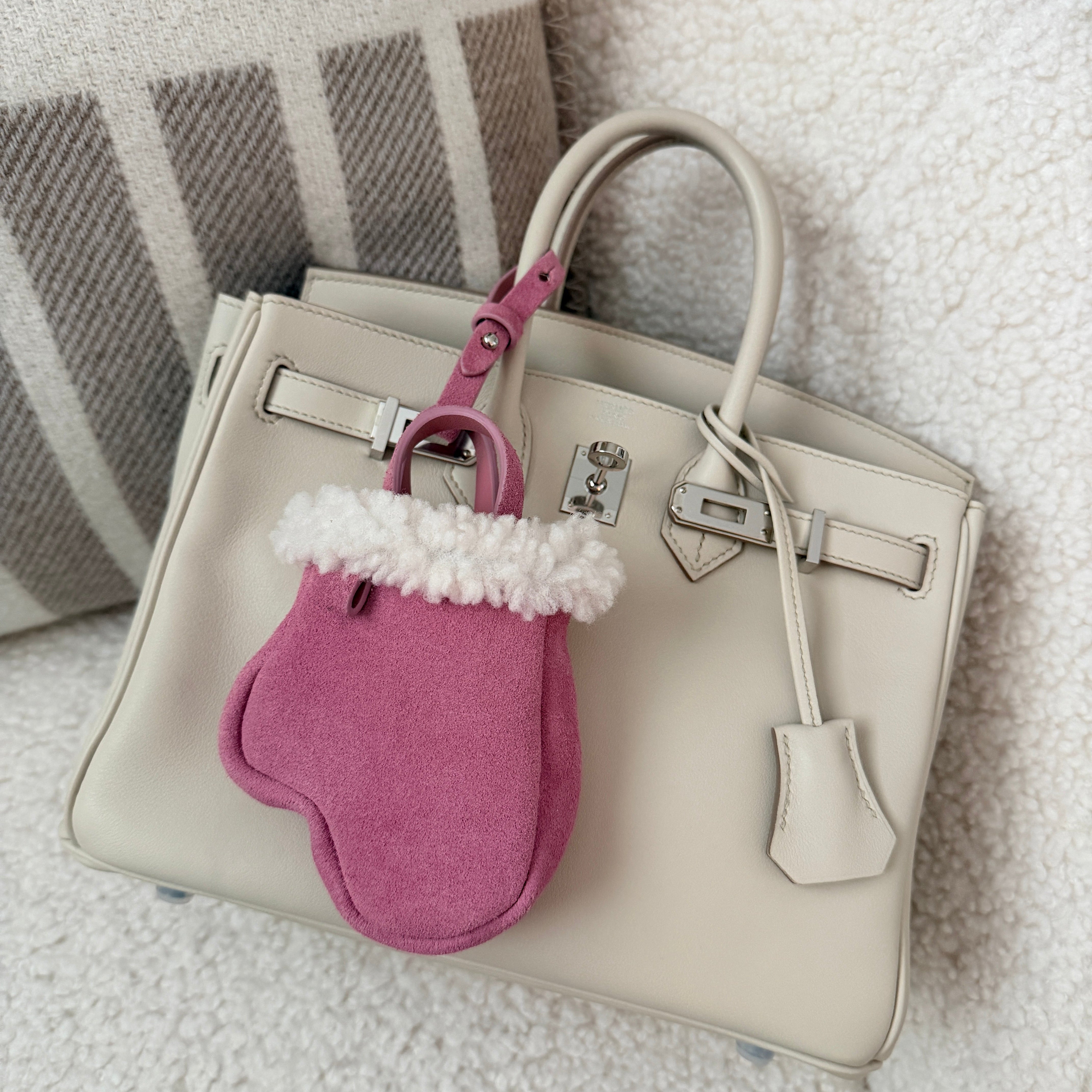 White Birkin handbag with a pink dog mitten on white sofa