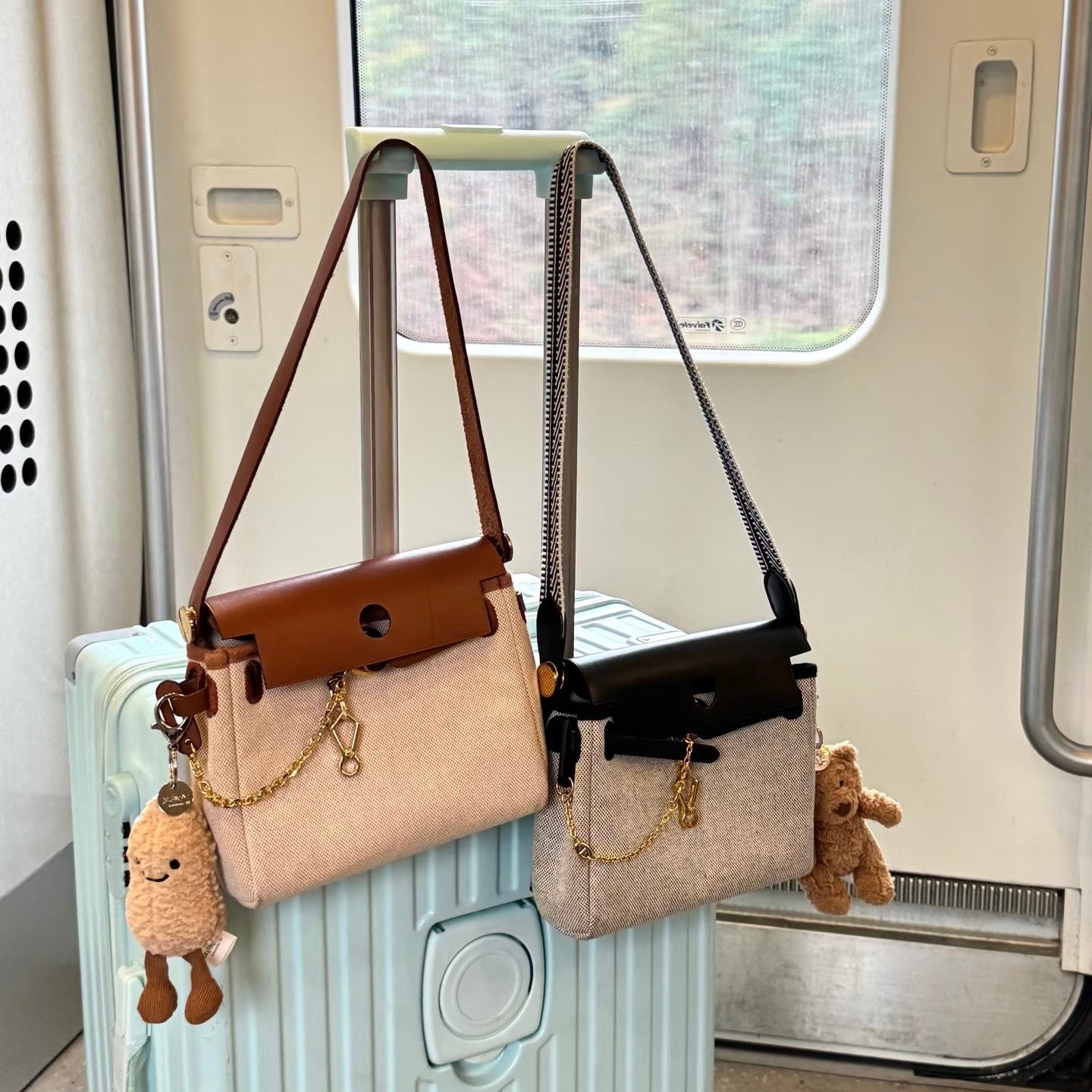 Two herbag on a suitcase with teddy bears attached, inside a train car.