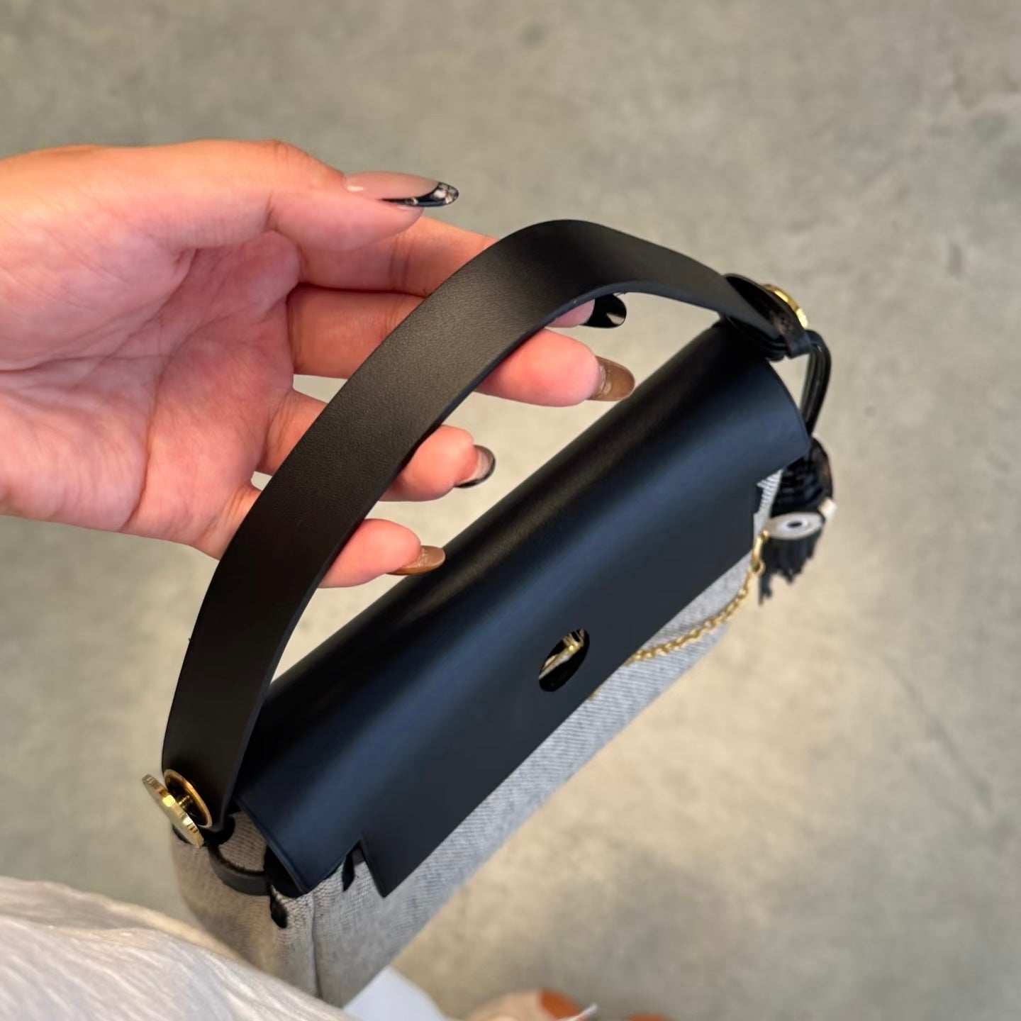 Black herbag held by a hand on a gray background