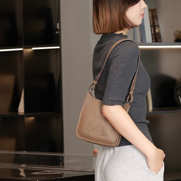 Woman carrying a Hermes Evelyne handbag in an indoor setting