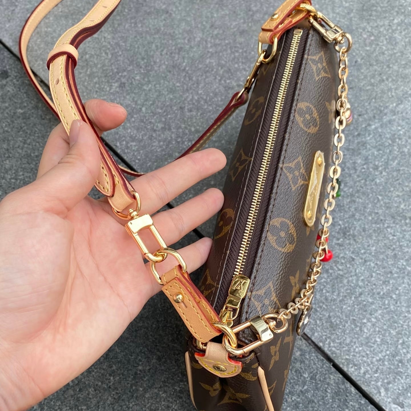 Hand holding a Louis Vuitton handbag with monogram pattern showing how to prevent wear and tear.