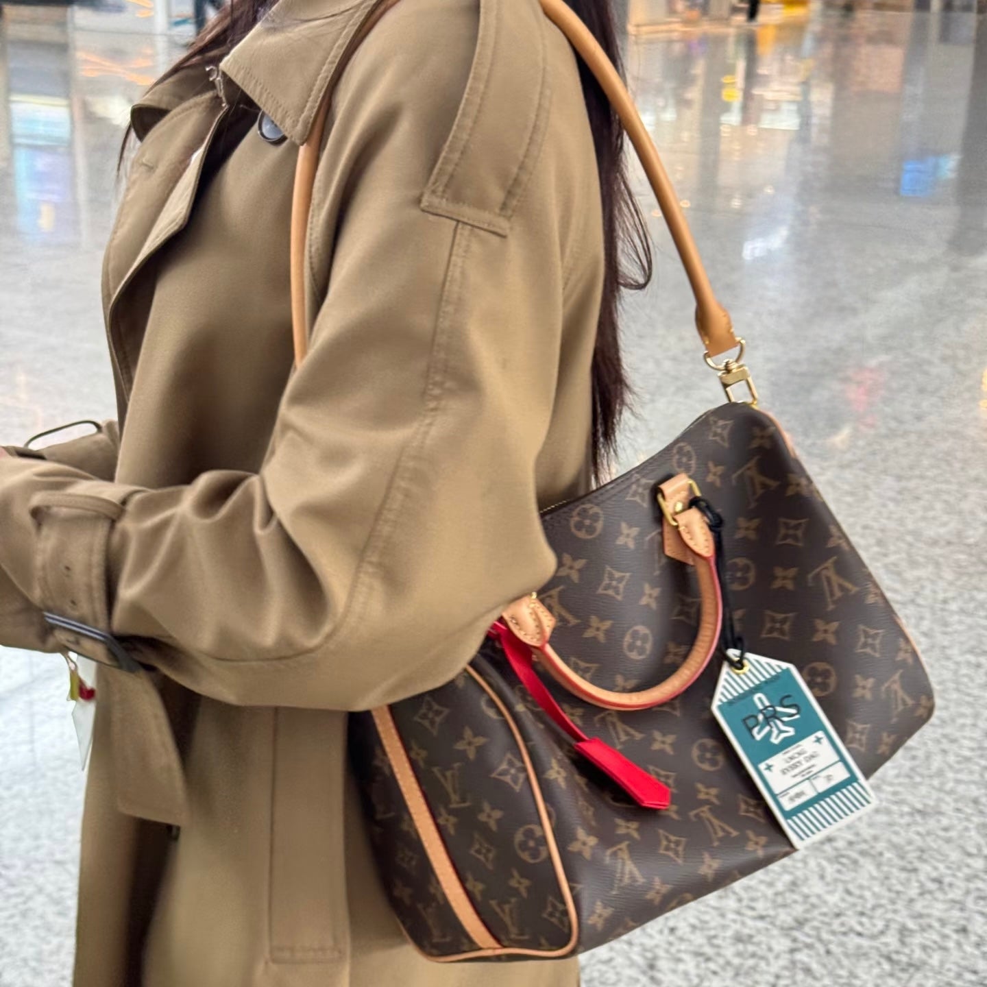 Person holding a Louis Vuitton speedy bag with lv speedy soft crafty at an airport 